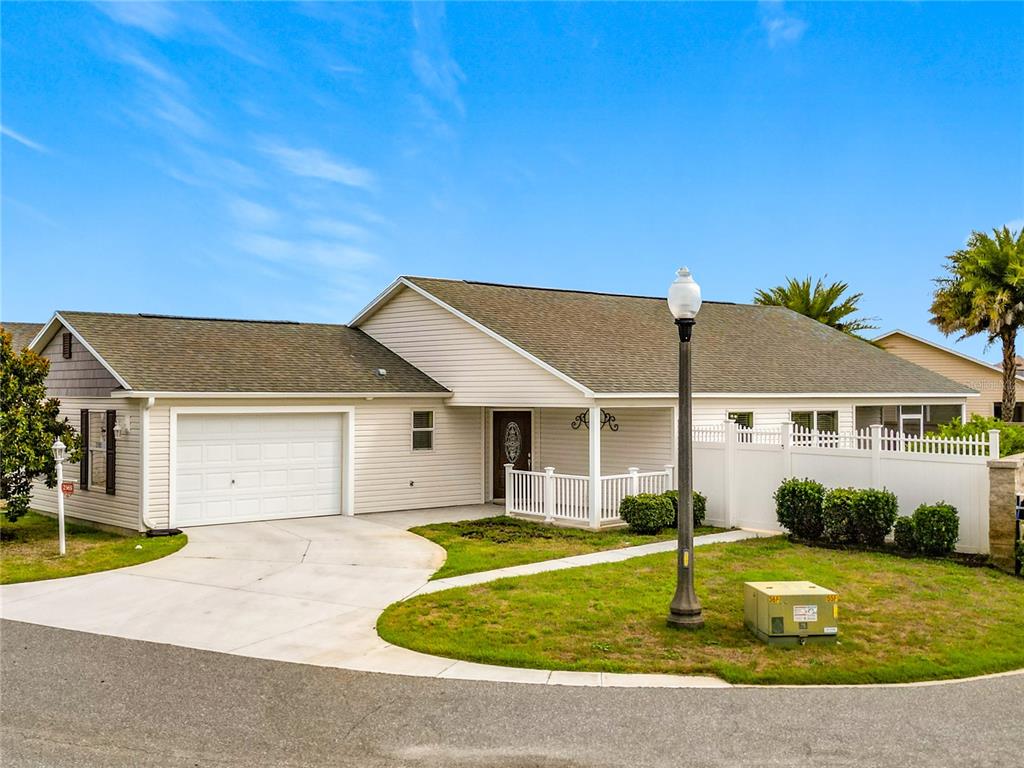 A single-story house with light siding, a white garage door, and a front porch — 2565 LINDEWOOD STREET, THE VILLAGES, FL