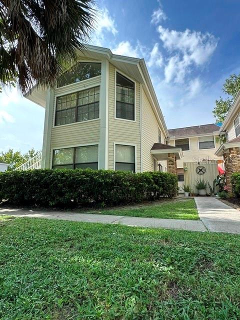A two-story house with light yellow siding and a large hedge in the front yard — 2803 FOX SQUIRREL, KISSIMMEE, FL