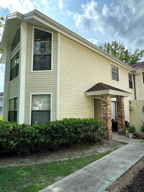A two-story house with light yellow siding features a brick-accented entryway and green landscaping — 2803 FOX SQUIRREL, KISSIMMEE, FL