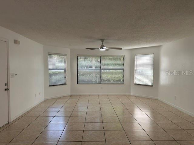 An empty room with beige tile flooring, white walls, and three windows with blinds — 2803 FOX SQUIRREL, KISSIMMEE, FL