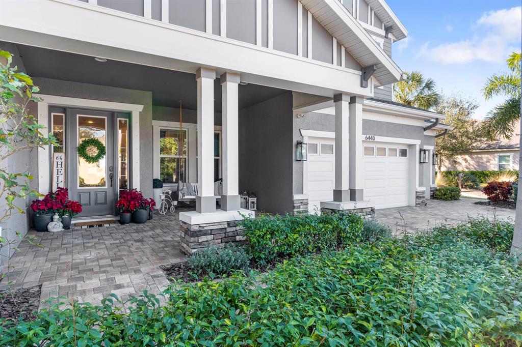 A gray house exterior features a covered front porch, stone pillars, and a paved driveway — 6440 TIDELINE DRIVE, APOLLO BEACH, FL