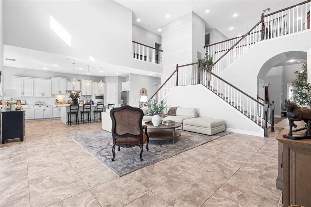 An open-concept living room and kitchen feature tile floors, a grand staircase, and white cabinetry — 6440 TIDELINE DRIVE, APOLLO BEACH, FL