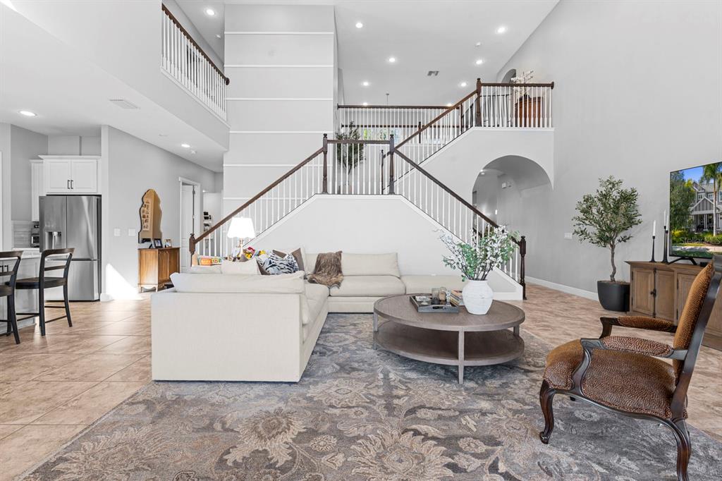 A spacious living room features a large sectional sofa, a central staircase, and tile flooring — 6440 TIDELINE DRIVE, APOLLO BEACH, FL