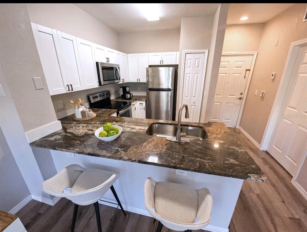 A kitchen features white cabinets, dark granite countertops, stainless steel appliances, and a breakfast bar — 1810 E PALM AVENUE UNIT 1210, TAMPA, FL