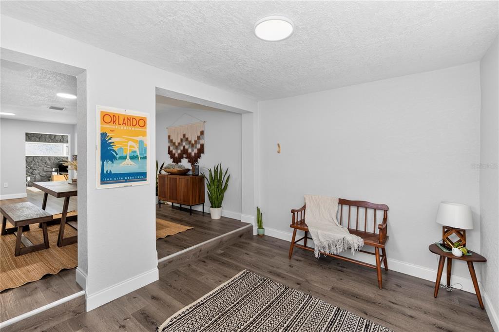 A living area features wood-look flooring, a wooden bench, and an opening to a dining room — 501 FITZGERALD DRIVE, MAITLAND, FL