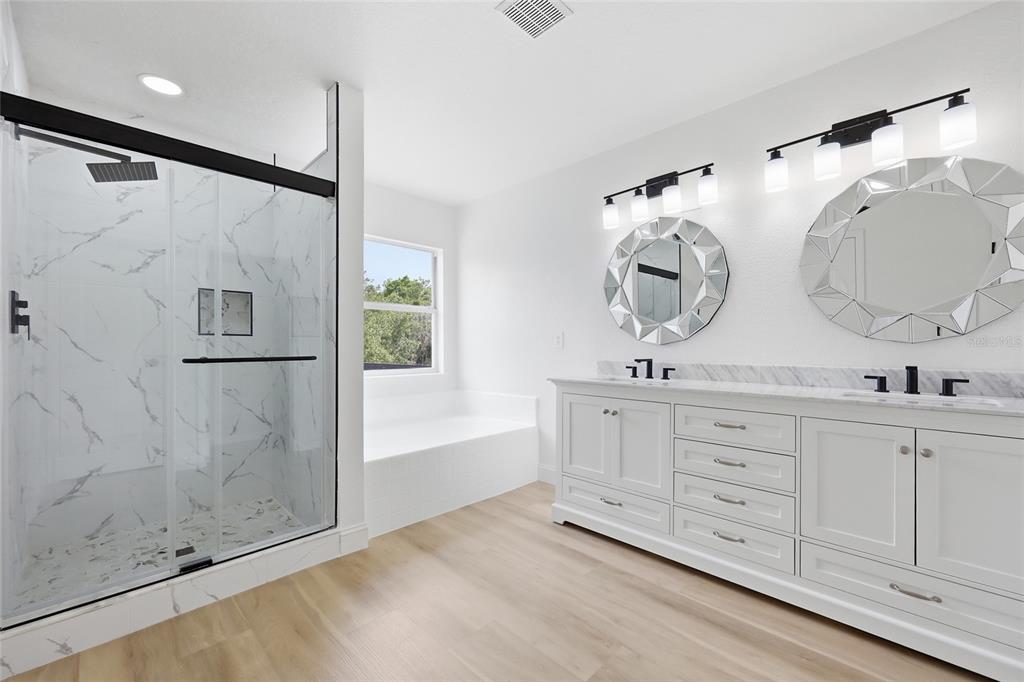 A modern bathroom features a glass-enclosed shower, a soaking tub, and a double vanity — 2124 CONTINENTAL STREET, ST CLOUD, FL