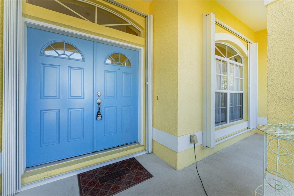 A bright blue double front door sits on a porch with yellow stucco walls — 225 FAIRWAY ROAD, ROTONDA WEST, FL