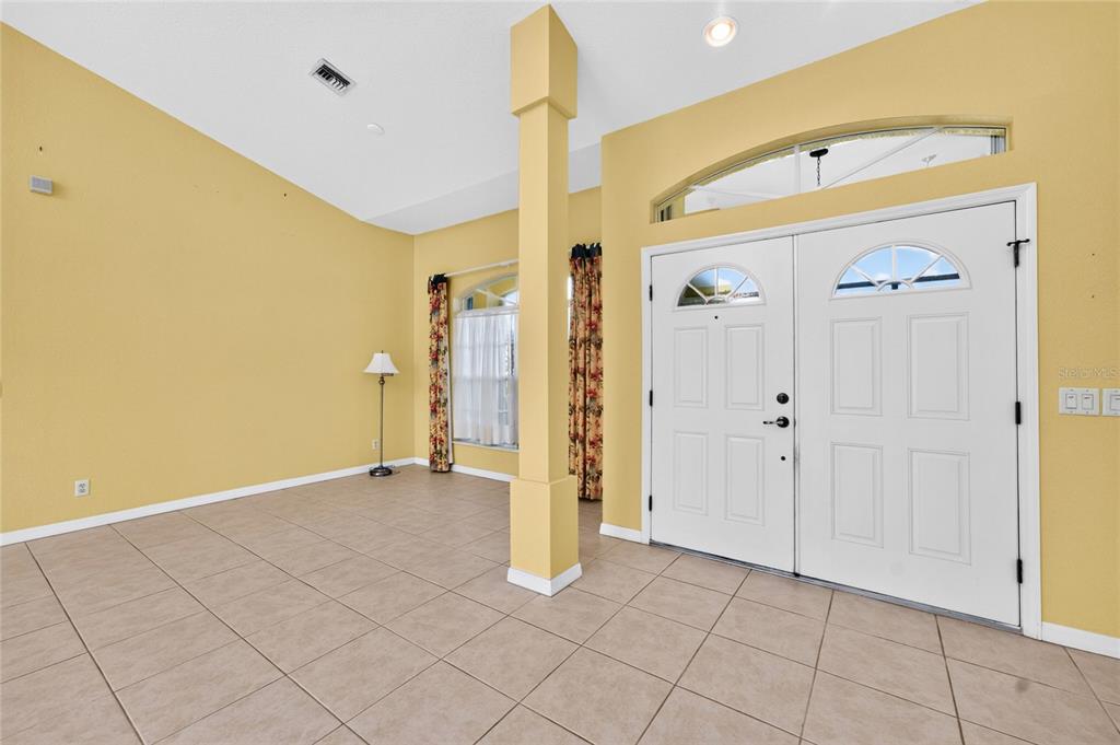 An entryway with yellow walls, tile flooring, a central column, and double front doors — 225 FAIRWAY ROAD, ROTONDA WEST, FL