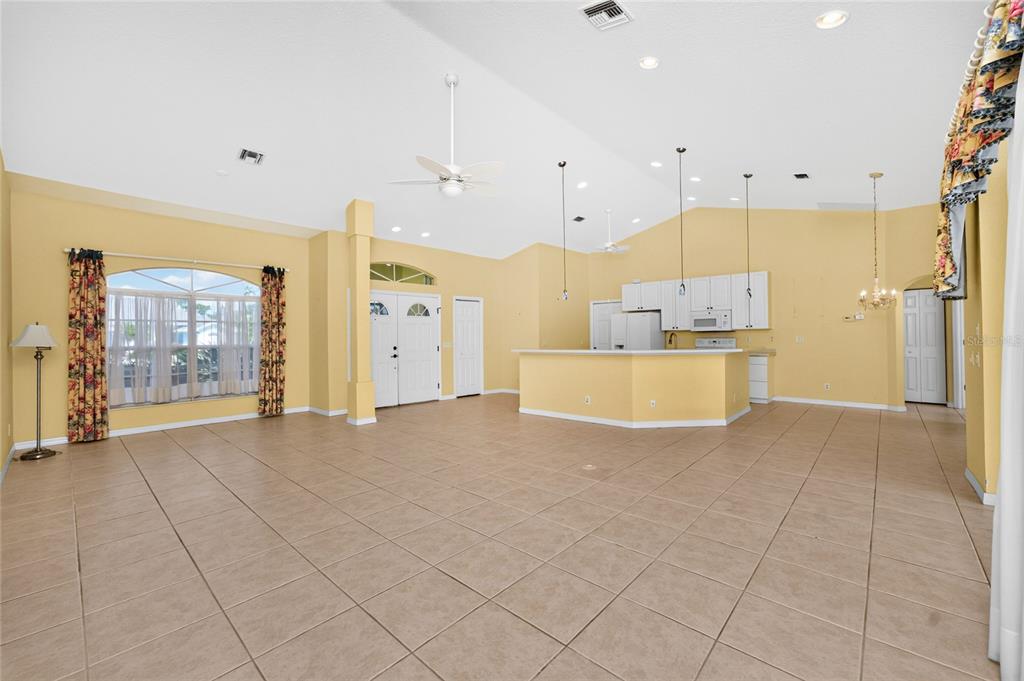 A spacious open-concept living area features light yellow walls, tile flooring, and a kitchen island — 225 FAIRWAY ROAD, ROTONDA WEST, FL