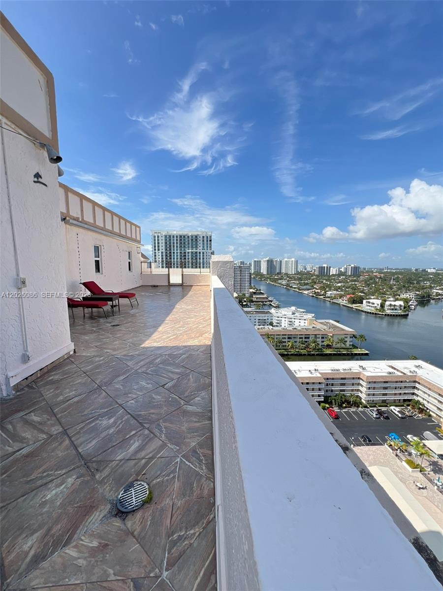 A high-rise balcony features tiled flooring, red lounge chairs, and a view of a waterway — 1865 S Ocean Drive # 21A, Hallandale Beach FL 33009, HALLANDALE BEACH, FL