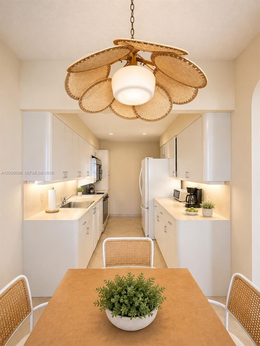 A galley kitchen features white cabinets, stainless steel appliances, and a rattan flower-shaped pendant light — 1865 S Ocean Drive # 21A, Hallandale Beach FL 33009, HALLANDALE BEACH, FL