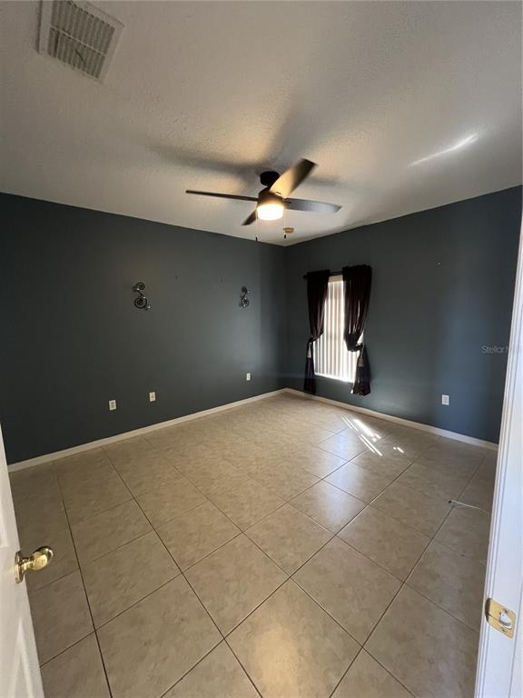 An empty room with dark gray walls, tile flooring, and a ceiling fan — 735 COLVILLE PLACE, KISSIMMEE, FL