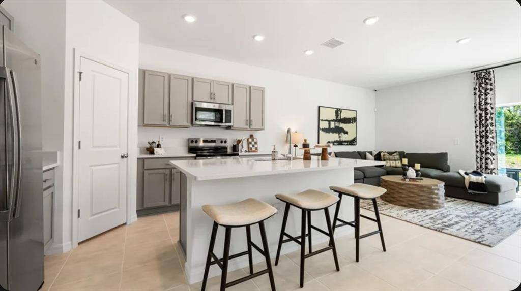 A kitchen with gray cabinets and a white island sits adjacent to a living room — 10822 ECLIPSE STREET, SARASOTA, FL