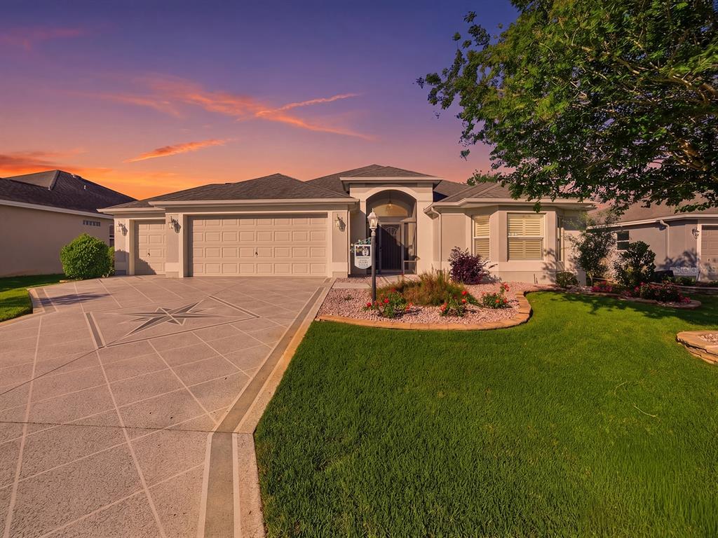 A single-story house with a decorative concrete driveway, a three-car garage, and a landscaped yard — 3332 DALKEITH TERRACE, THE VILLAGES, FL