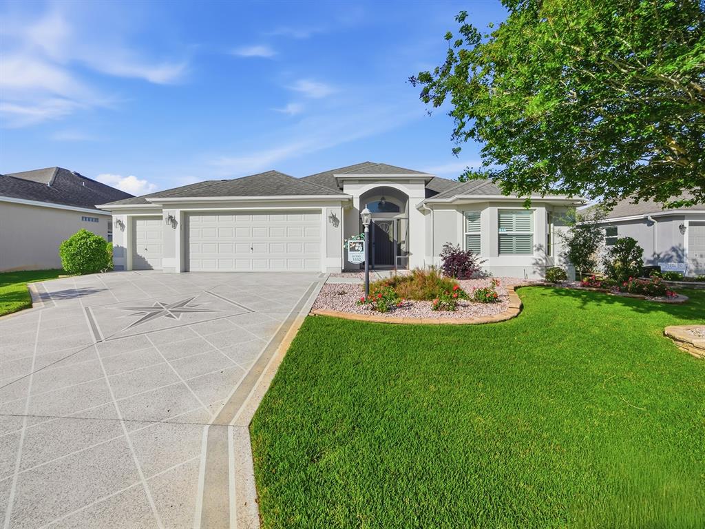 A single-story house with a three-car garage, decorative concrete driveway, and landscaped front yard — 3332 DALKEITH TERRACE, THE VILLAGES, FL