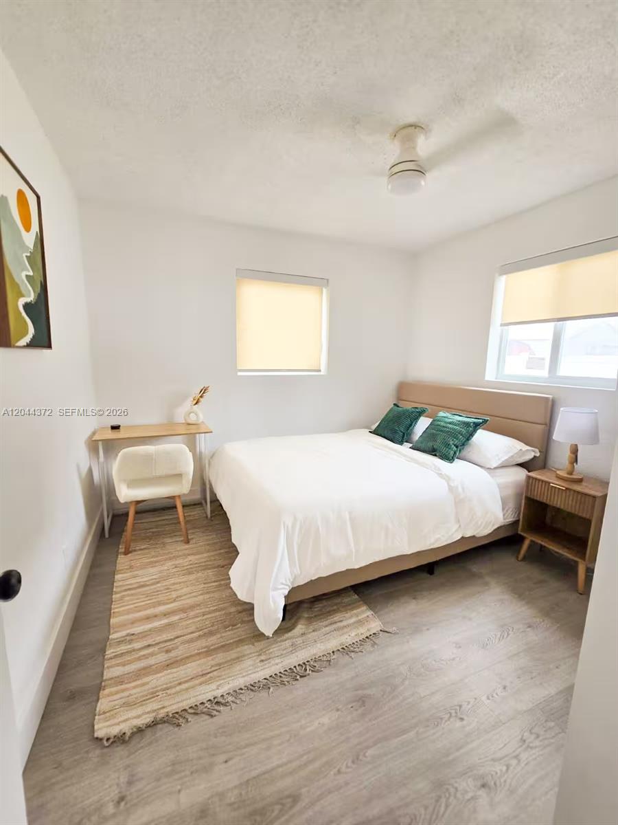 A bedroom features a bed, a small desk with a chair, and light wood flooring — 5712 Mayo St # 1, Hollywood FL 33023, HOLLYWOOD, FL