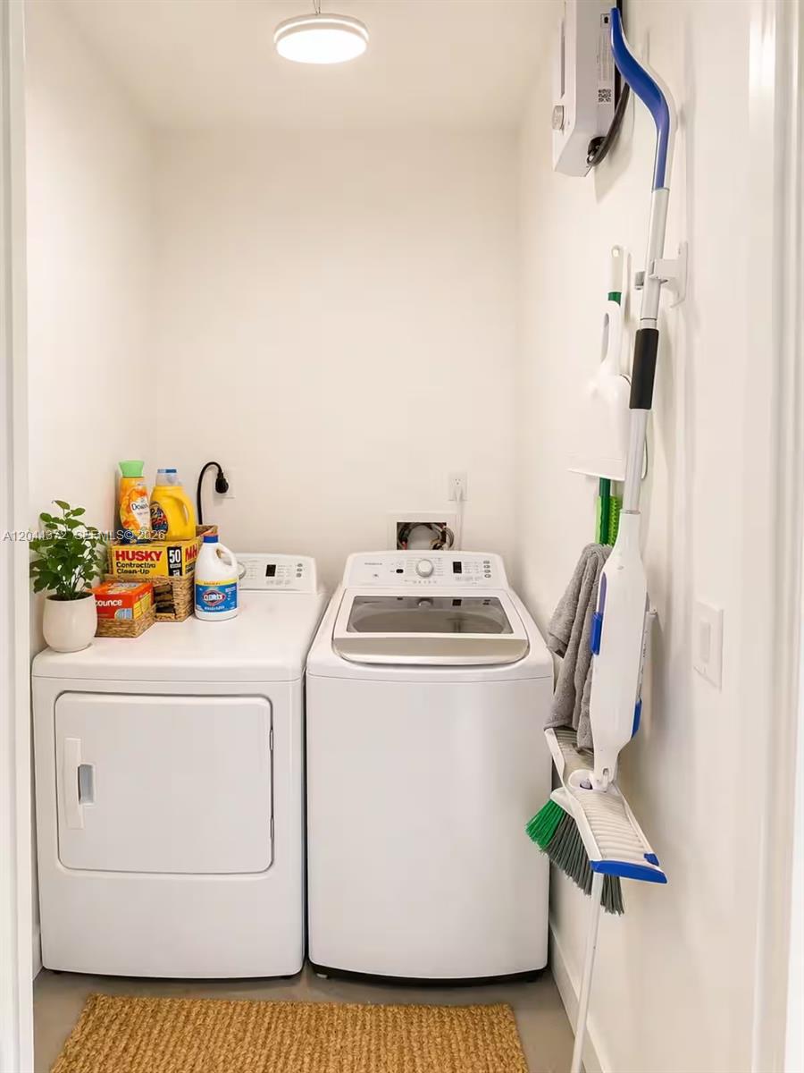 A laundry closet features a white washer and dryer with cleaning supplies and wall-mounted tools — 5712 Mayo St # 1, Hollywood FL 33023, HOLLYWOOD, FL
