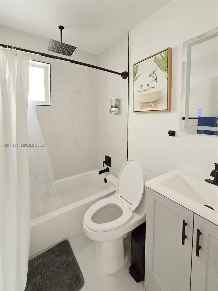 A bathroom features a white bathtub, a toilet, and a vanity with a mirror — 5712 Mayo St # 1, Hollywood FL 33023, HOLLYWOOD, FL