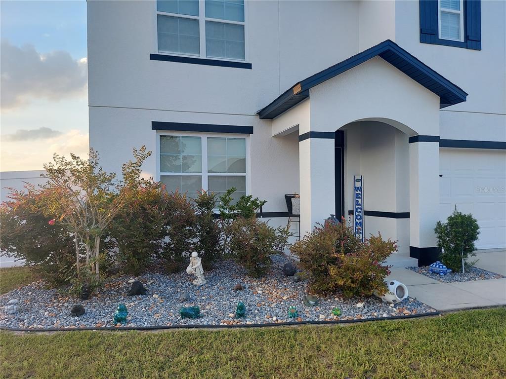 A two-story house exterior features white stucco walls, dark blue trim, and a landscaped front yard — 4551 NE 27TH STREET, OCALA, FL