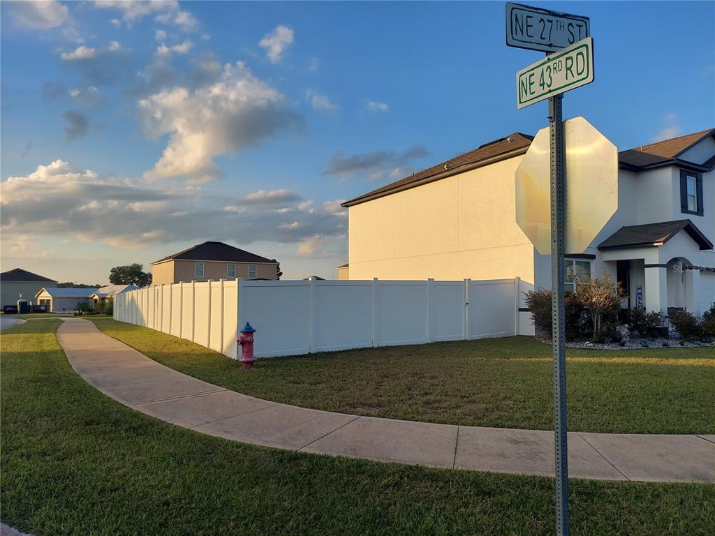A street corner view showing a white vinyl fence, a sidewalk, and a fire hydrant — 4551 NE 27TH STREET, OCALA, FL