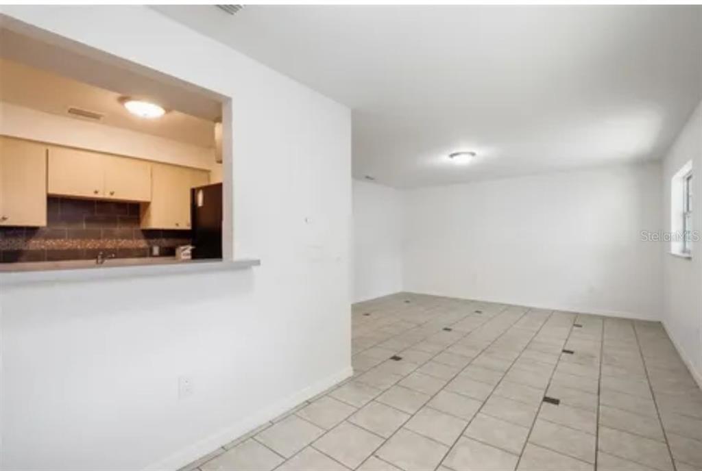 A view of a tiled living area with a pass-through opening to the kitchen — 519 S WESTGATE AVENUE, LAKELAND, FL