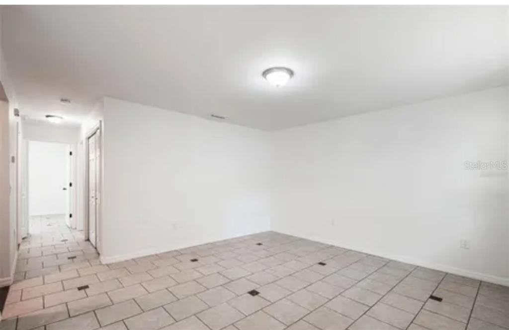 An empty room with white walls, a ceiling light fixture, and light-colored tiled flooring — 519 S WESTGATE AVENUE, LAKELAND, FL