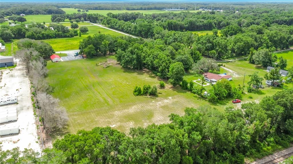An aerial view shows a large grassy lot with a house, trees, and outbuildings — 5298 CR 542F, BUSHNELL, FL