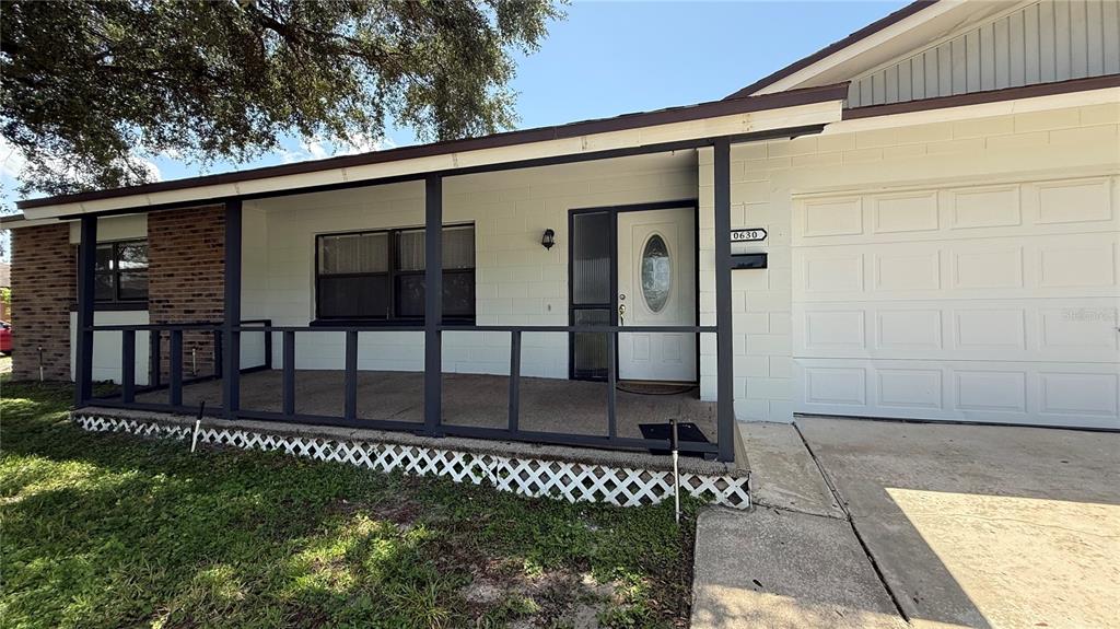 A single-story house features a white block exterior, a covered front porch, and a garage — 10630 EASTVIEW DRIVE, ORLANDO, FL