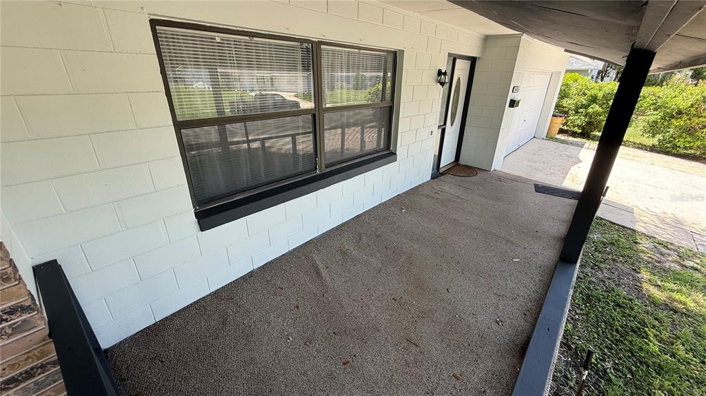 A covered concrete porch features a large window, a front door, and a garage entrance — 10630 EASTVIEW DRIVE, ORLANDO, FL