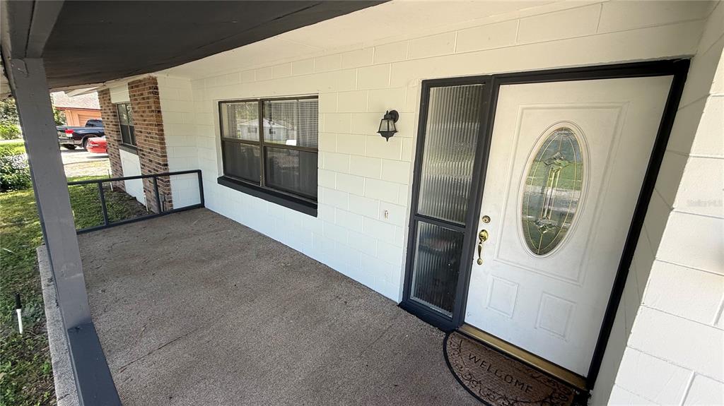 A covered concrete porch features a white front door with an oval glass insert — 10630 EASTVIEW DRIVE, ORLANDO, FL