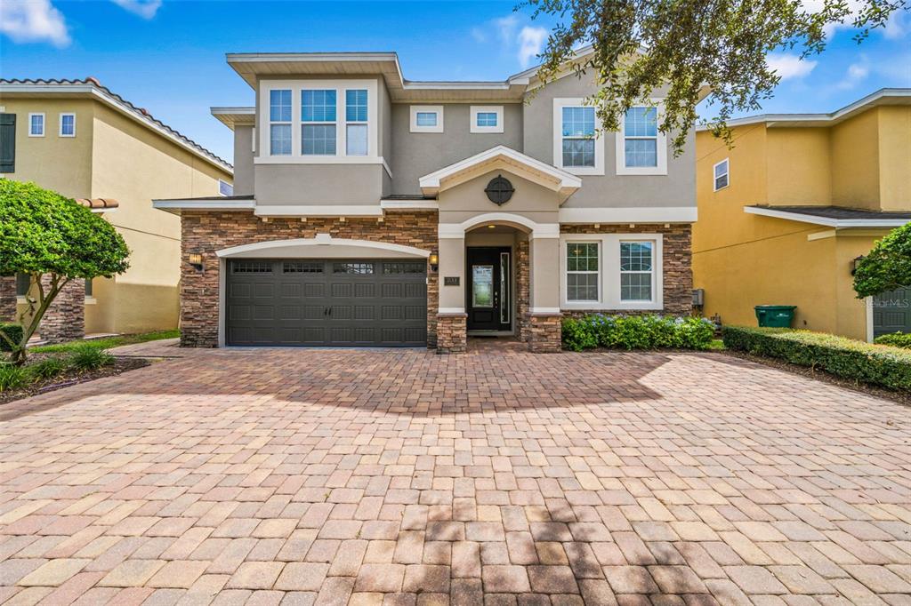A two-story suburban house with a stone facade, a paved driveway, and a two-car garage — 231 LASSO DRIVE, KISSIMMEE, FL