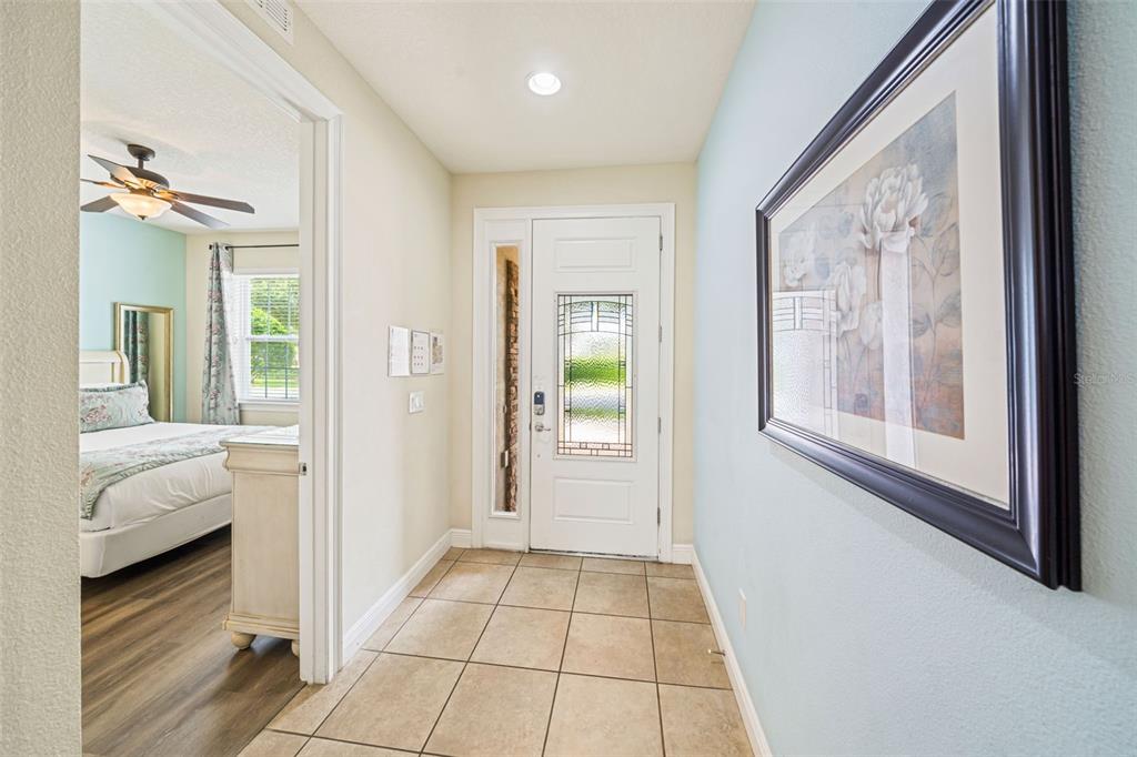 An entryway with tile flooring leads to a front door and an adjacent bedroom — 231 LASSO DRIVE, KISSIMMEE, FL