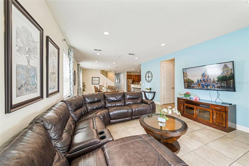 A living room features a large brown leather sectional, a glass coffee table, and a television — 231 LASSO DRIVE, KISSIMMEE, FL