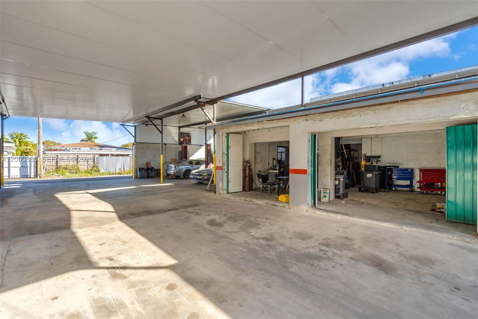 An open-air garage features a concrete floor, metal roof, and two open service bays — 3219 SW 8th St, Miami FL 33135, MIAMI, FL