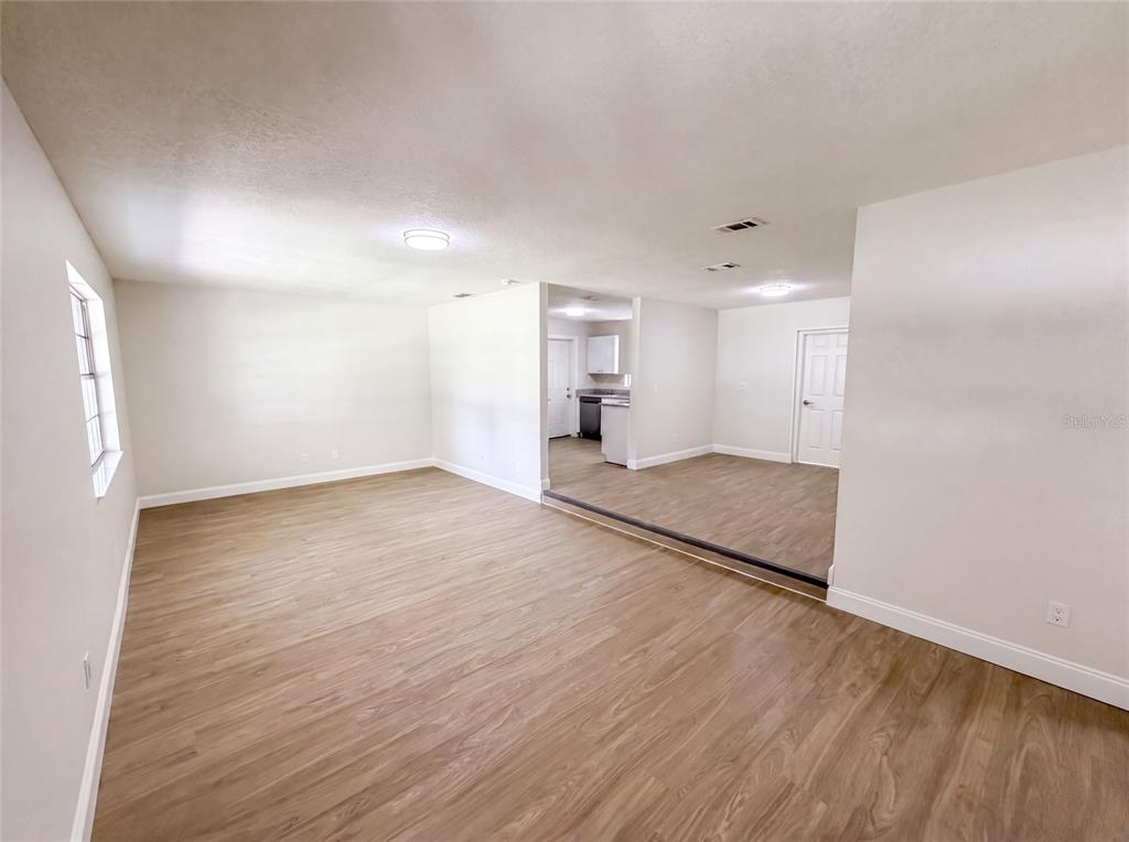 An open-concept living area features light wood-look flooring and a step-down kitchen area — 585 HEWETT DRIVE, ORLANDO, FL