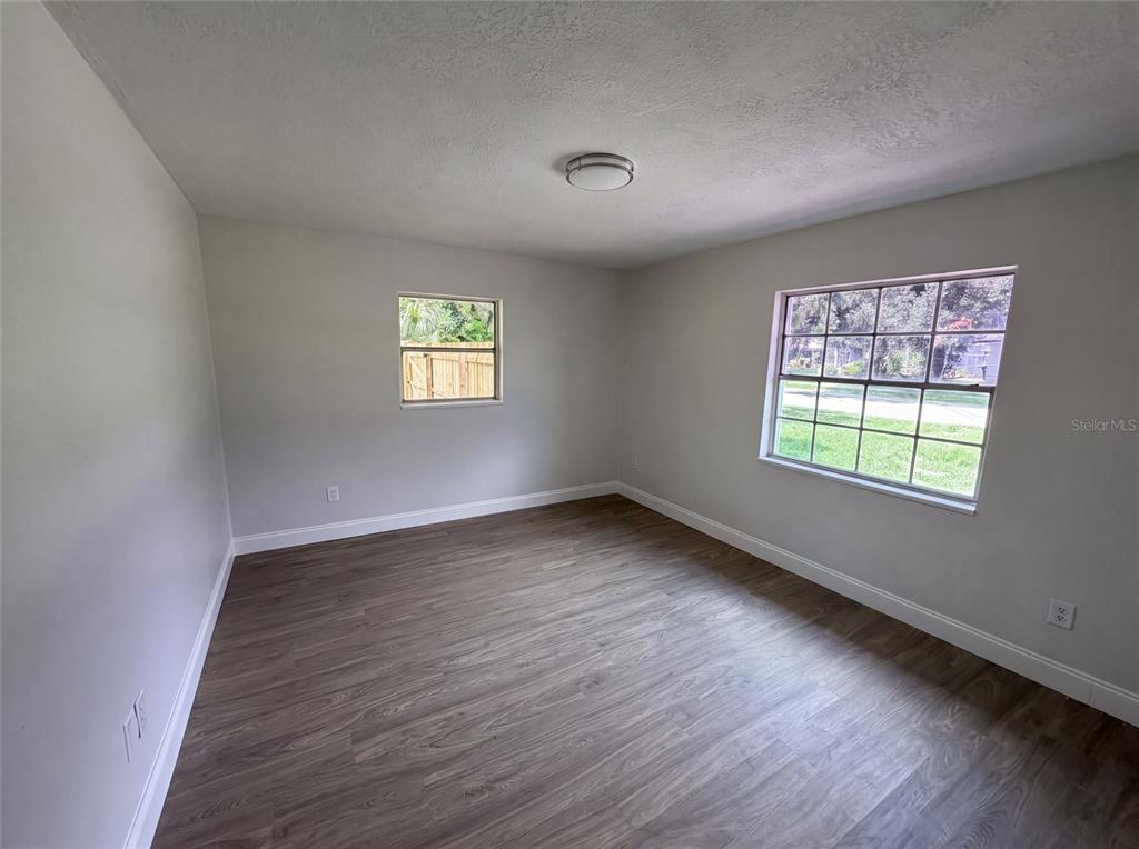 An empty bedroom features light gray walls, wood-look flooring, and two windows — 585 HEWETT DRIVE, ORLANDO, FL