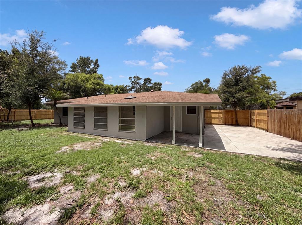 The exterior of a single-story house features a concrete patio and a wooden fence — 585 HEWETT DRIVE, ORLANDO, FL