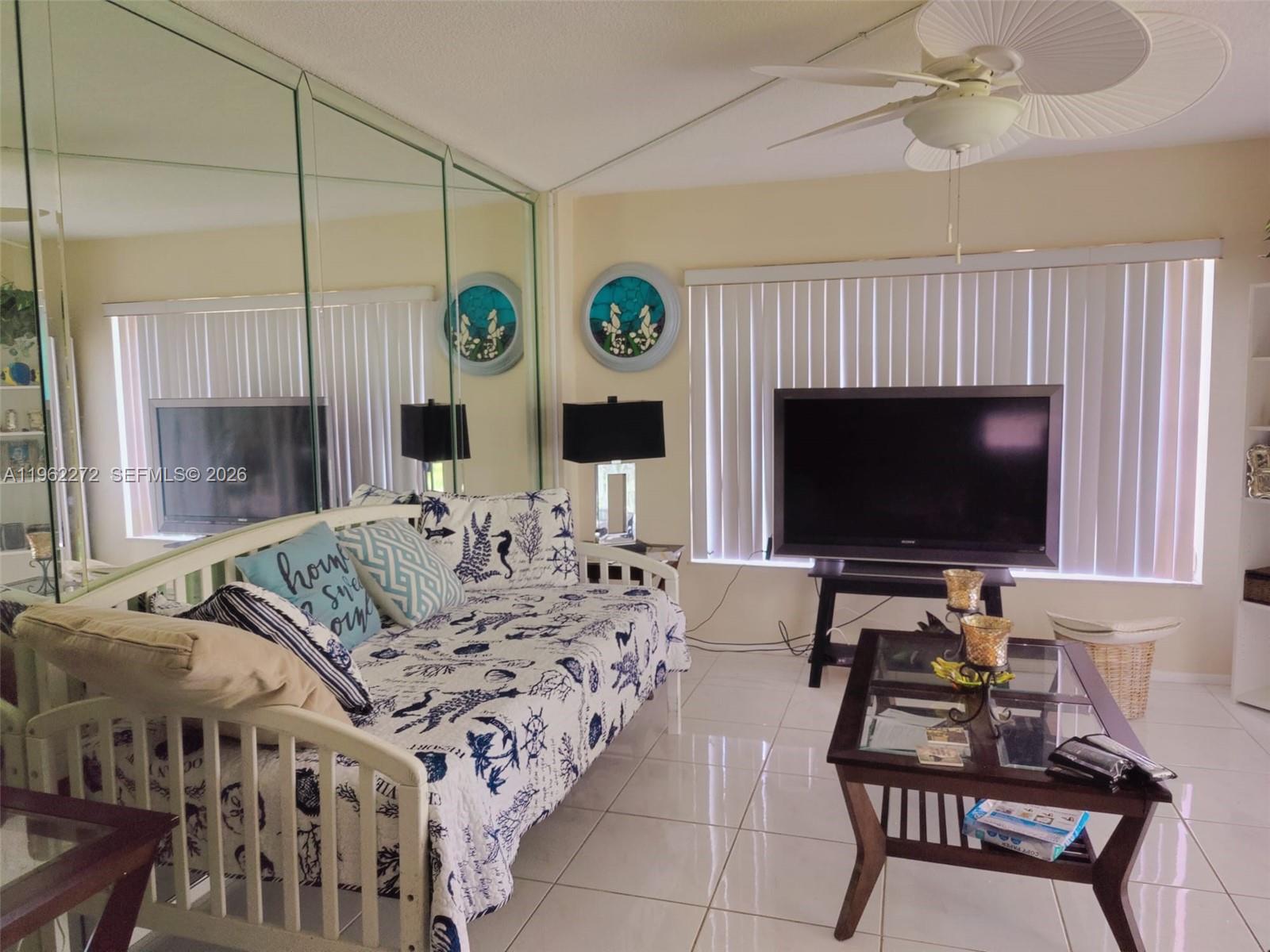 A living room features a daybed, a television on a stand, and mirrored wall panels — 4168 Inverrary Dr # 301, Lauderhill FL 33319, LAUDERHILL, FL