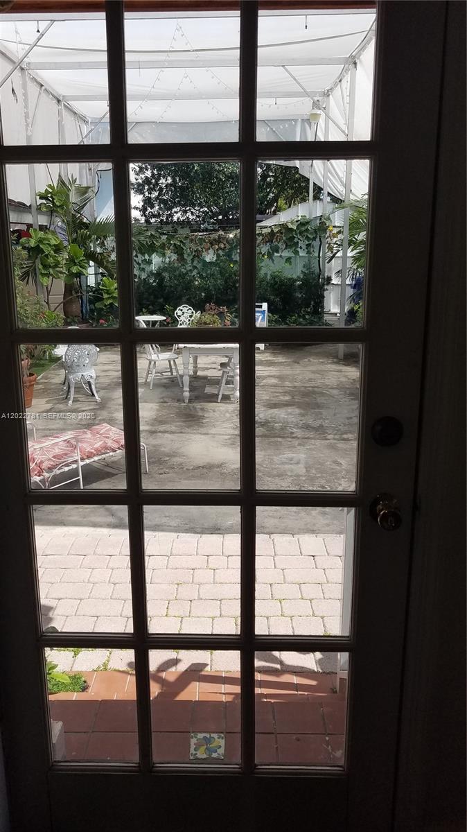 A view through a glass-paned door looking out onto a patio with outdoor furniture — 1239 Alton Rd # 2, Miami Beach FL 33139, MIAMI BEACH, FL