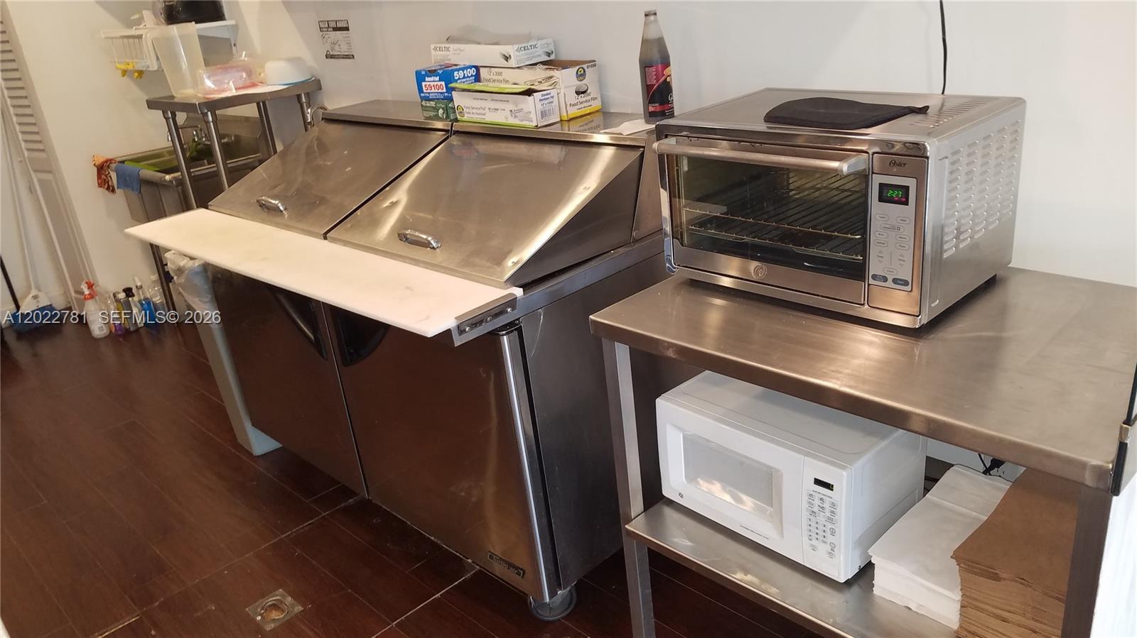 A commercial kitchen features stainless steel prep tables, a refrigerated sandwich unit, and countertop appliances — 1239 Alton Rd # 2, Miami Beach FL 33139, MIAMI BEACH, FL