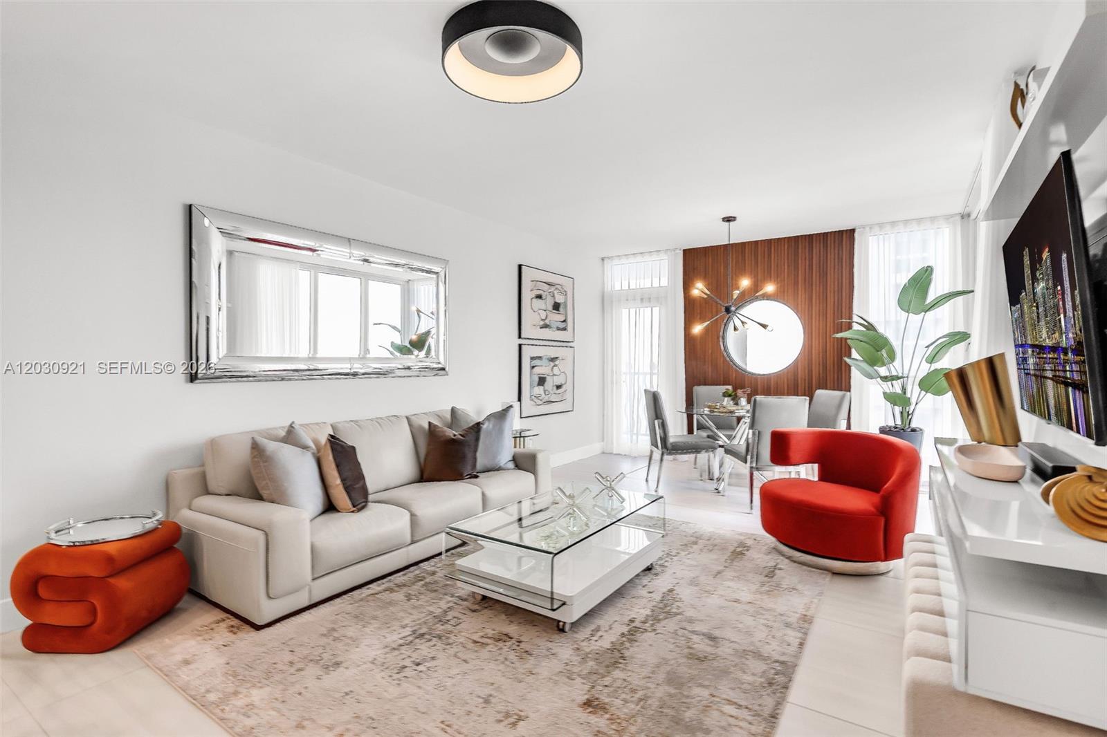 A modern living and dining room features a white sofa, red chair, and wood-paneled wall — 1500 OCEAN DR # 707, Miami Beach FL 33139, MIAMI BEACH, FL