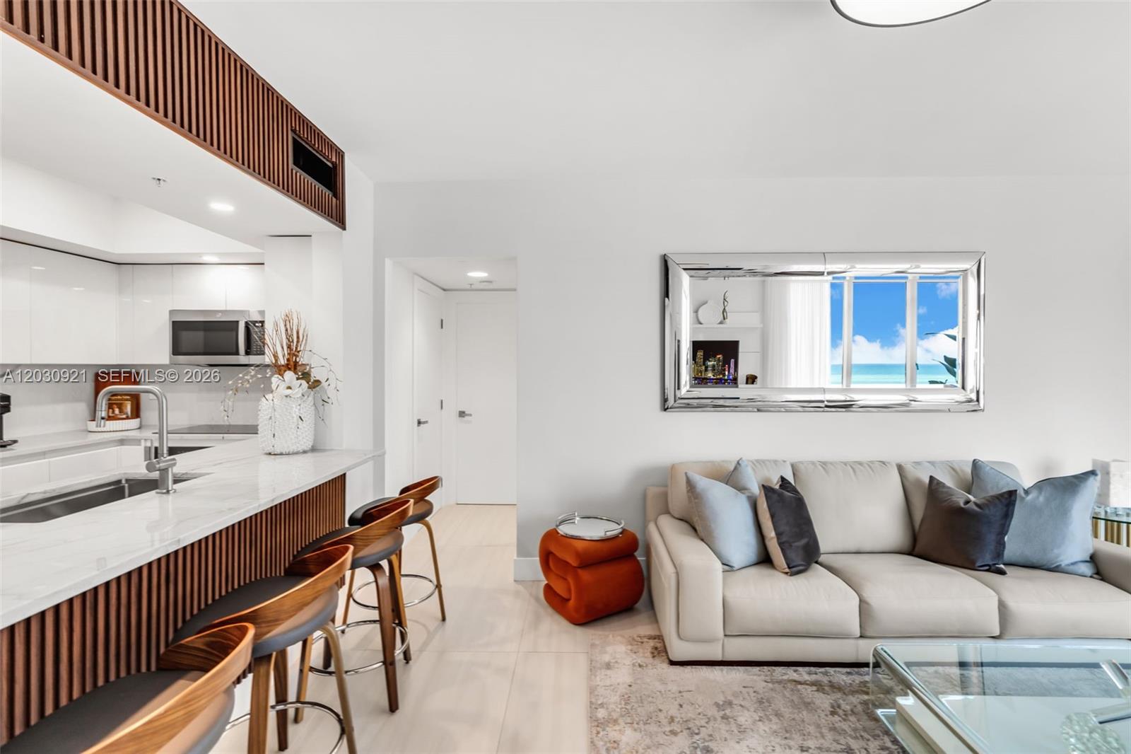 A modern living room features a kitchen island with bar stools and a white sofa — 1500 OCEAN DR # 707, Miami Beach FL 33139, MIAMI BEACH, FL