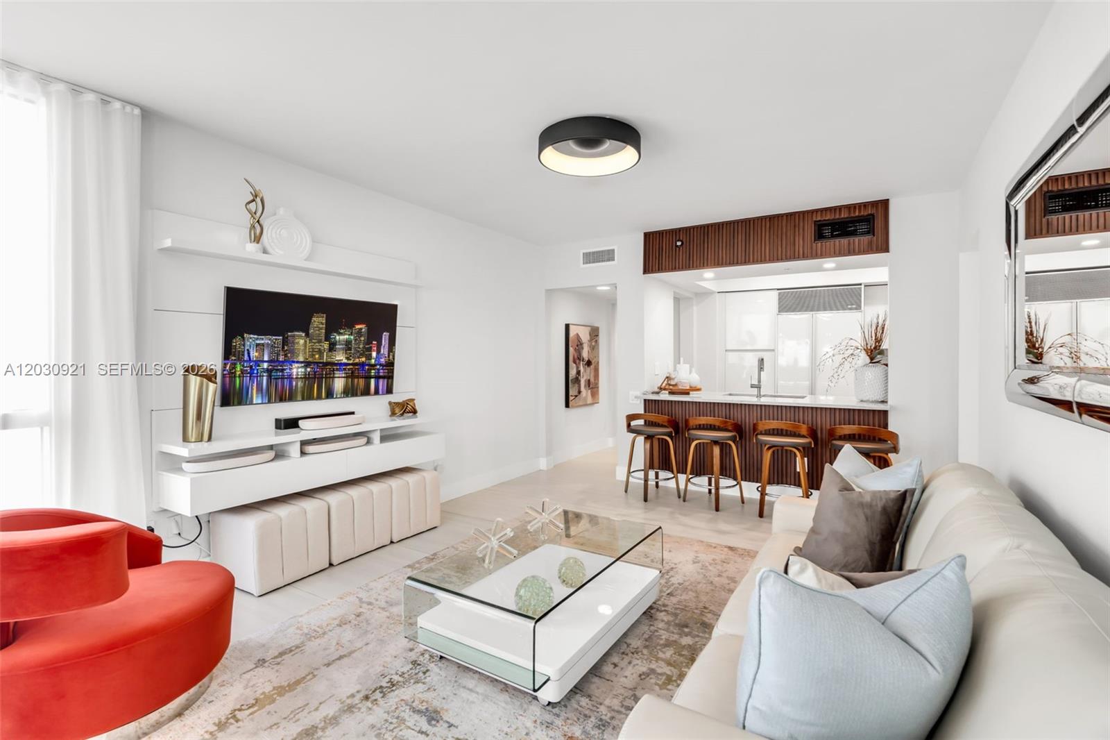 A modern living room features a white media console, a glass coffee table, and bar seating — 1500 OCEAN DR # 707, Miami Beach FL 33139, MIAMI BEACH, FL