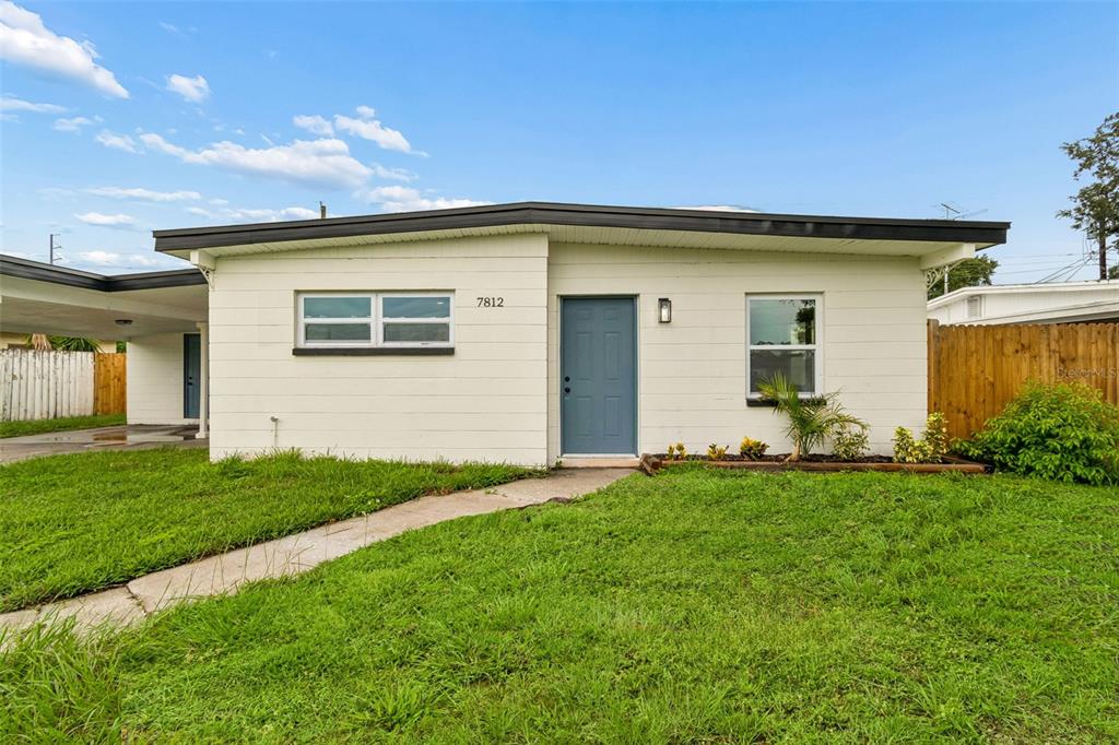 A single-story white house with a blue front door and a concrete walkway — 7812 EGYPT LAKE DRIVE, TAMPA, FL