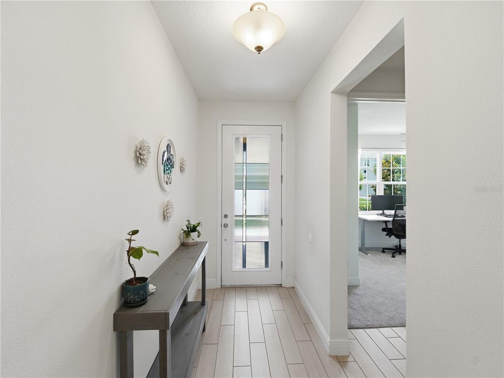 A bright entryway features a console table, wall decor, and a glass-paneled front door — 5040 BESSIE COURT, ST CLOUD, FL