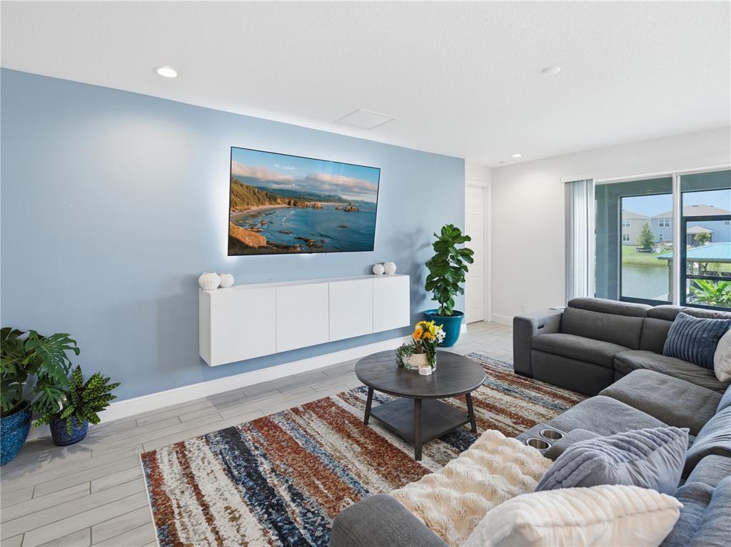 A living room features a light blue accent wall, a floating cabinet, and a sectional sofa — 5040 BESSIE COURT, ST CLOUD, FL