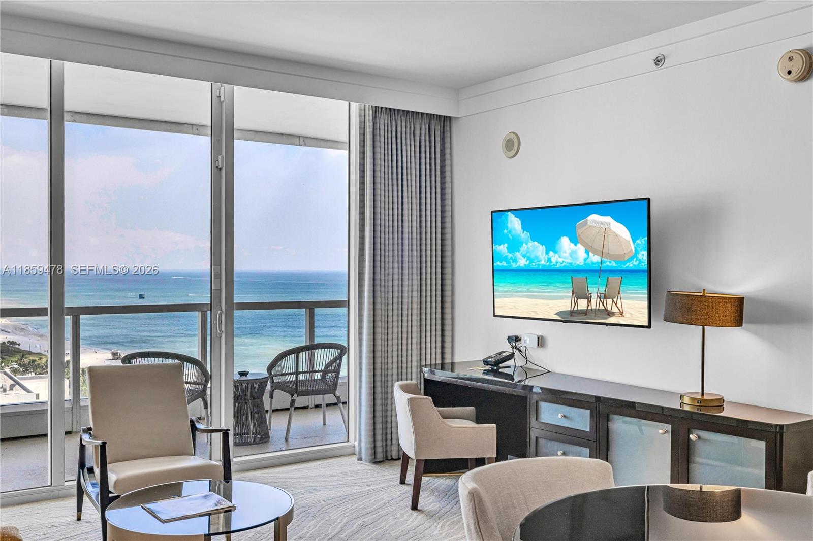 A hotel room features a desk, television, seating area, and a balcony overlooking the ocean — 4391 Collins Ave, Miami Beach FL 33140, MIAMI BEACH, FL