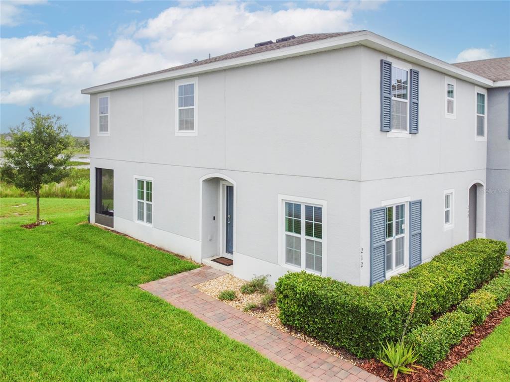 A two-story light gray townhouse with blue shutters and a brick walkway — 212 PRIMROSE DRIVE, DAVENPORT, FL