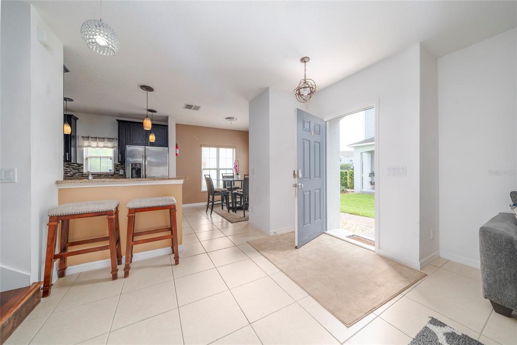 An open-concept entryway leads to a kitchen with bar seating and a dining area — 212 PRIMROSE DRIVE, DAVENPORT, FL