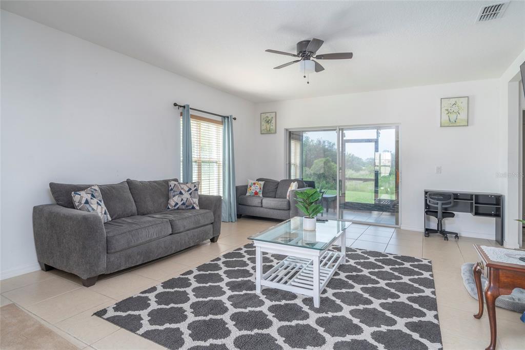 A living room features gray sofas, a white coffee table, and a sliding glass door — 212 PRIMROSE DRIVE, DAVENPORT, FL